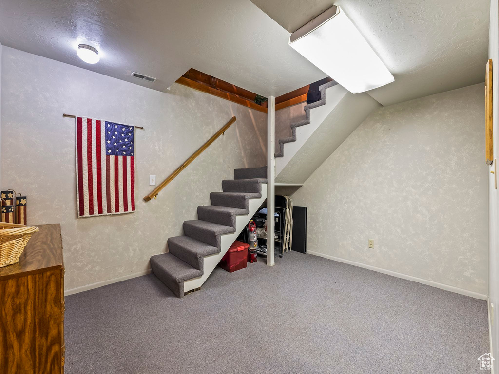 Basement featuring carpet floors, stairway, and a textured ceiling