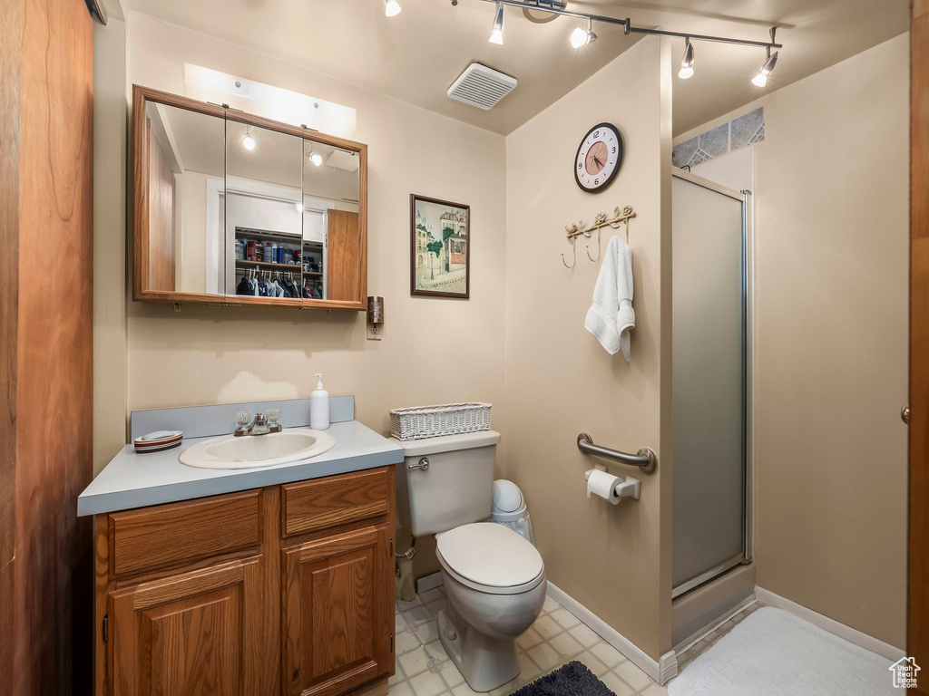Bathroom featuring a stall shower, vanity, rail lighting, and tile patterned floors