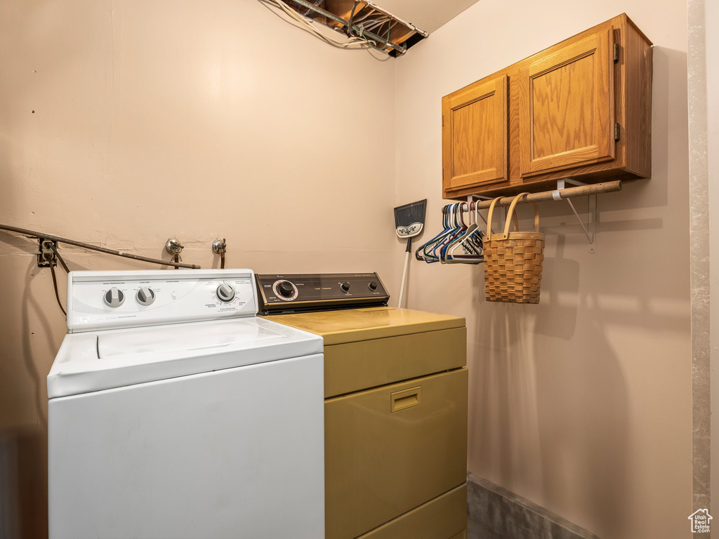 Washroom featuring cabinet space and washer and clothes dryer