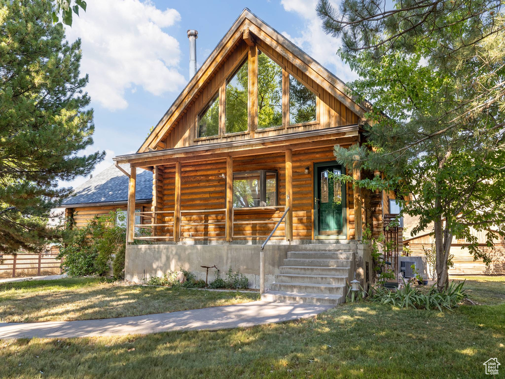 Log-style house with a porch, a front lawn, and log exterior