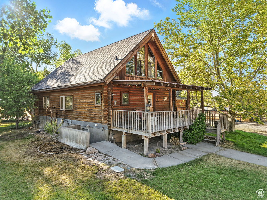 Rear view of property featuring a shingled roof, a yard, and a deck