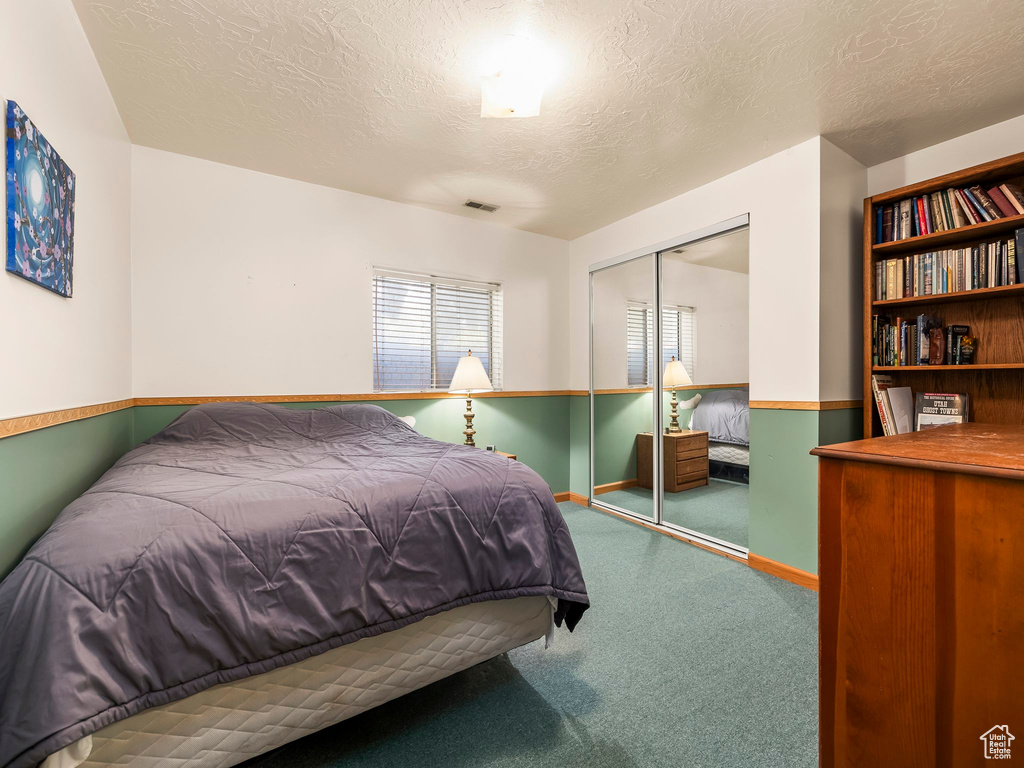Carpeted bedroom with a closet and a textured ceiling