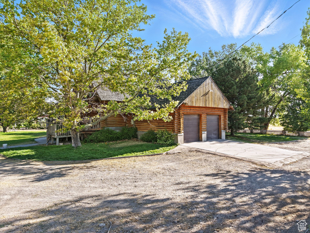 View of front of home with log siding, a garage, roof with shingles, and a front yard