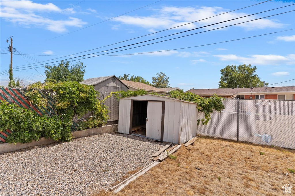 Fenced backyard featuring a storage shed