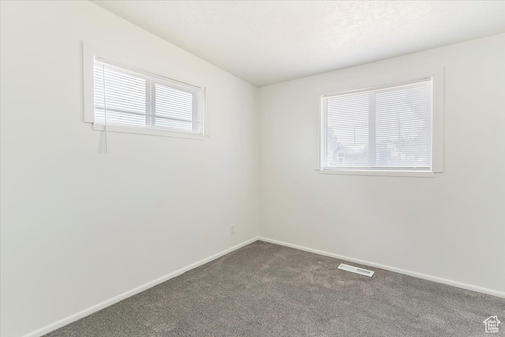 Unfurnished room featuring baseboards and dark carpet