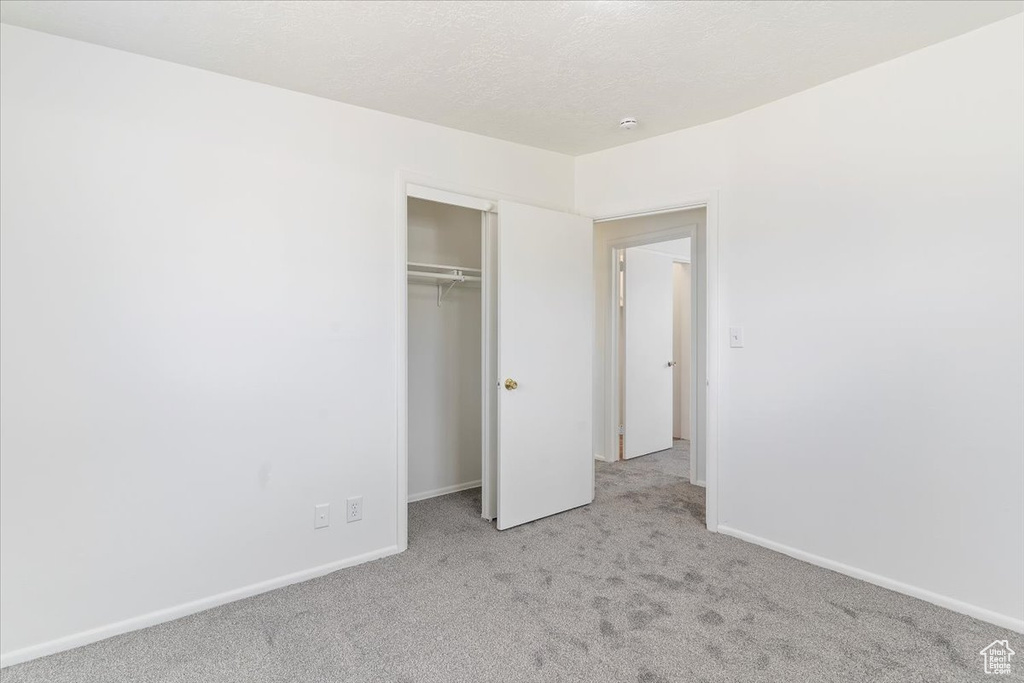 Unfurnished bedroom featuring light colored carpet and a closet