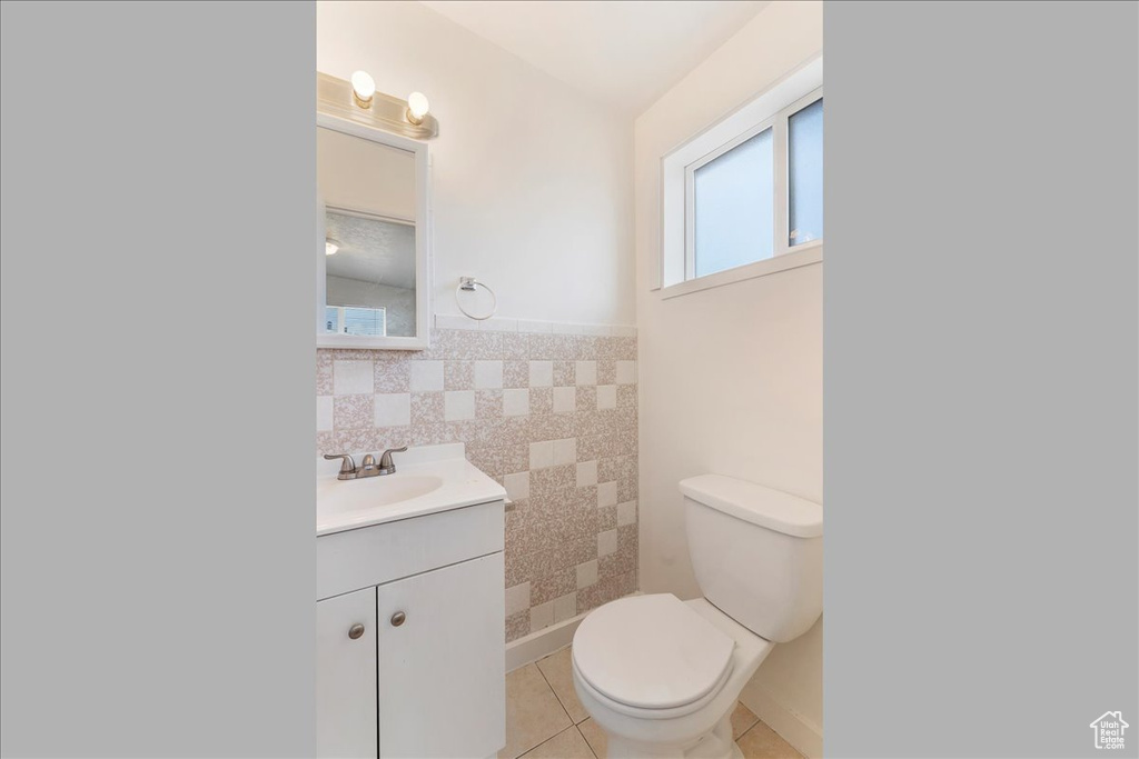Bathroom featuring vanity, tile patterned flooring, tile walls, and wainscoting