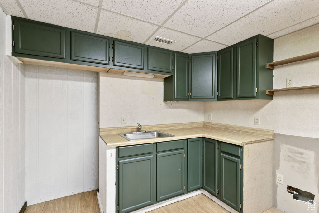 Kitchen with a paneled ceiling, green cabinets, light countertops, and light wood finished floors