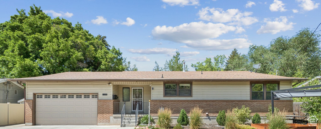View of front of property with brick siding, a garage, and driveway