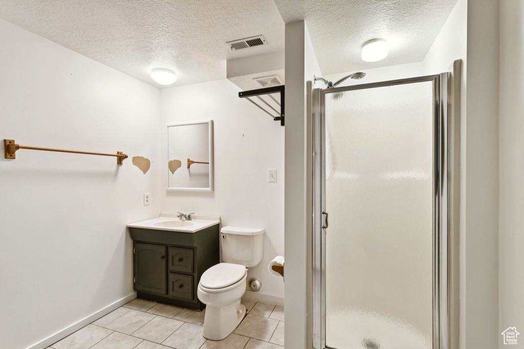 Full bathroom featuring a textured ceiling, vanity, a shower stall, and tile patterned flooring