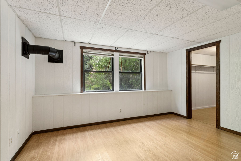 Unfurnished bedroom featuring wood finished floors, a walk in closet, and a paneled ceiling