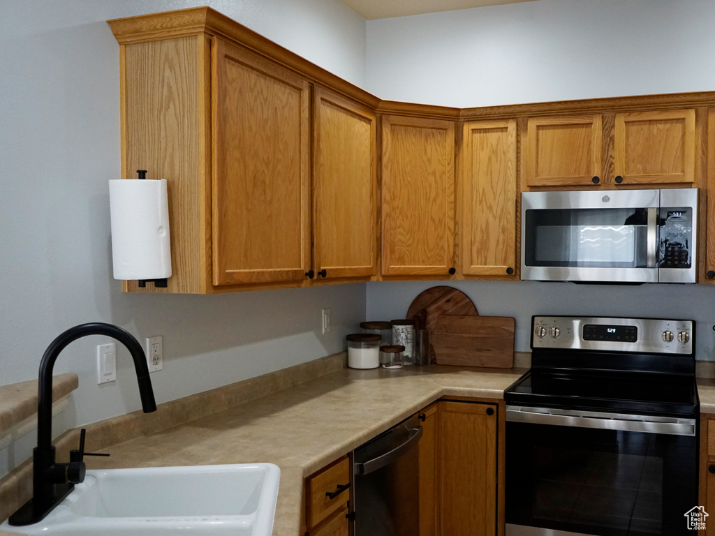 Kitchen featuring stainless steel appliances, light countertops, and brown cabinets