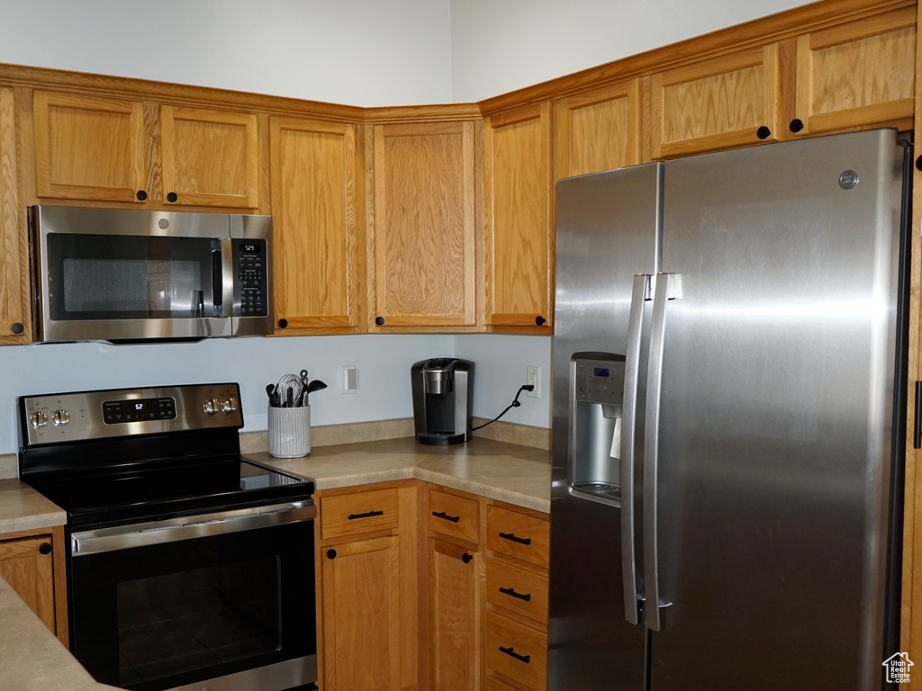 Kitchen with appliances with stainless steel finishes, light countertops, and brown cabinets