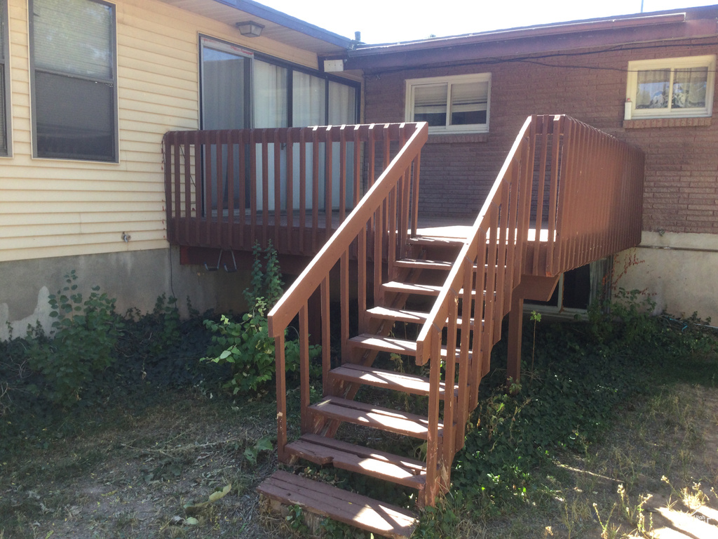 View of exterior entry featuring a deck and brick siding