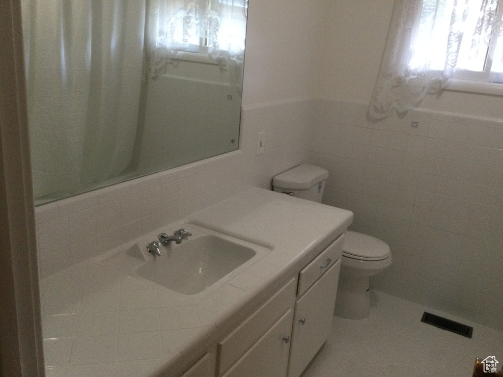 Bathroom featuring tile walls, vanity, tile patterned flooring, and a wainscoted wall