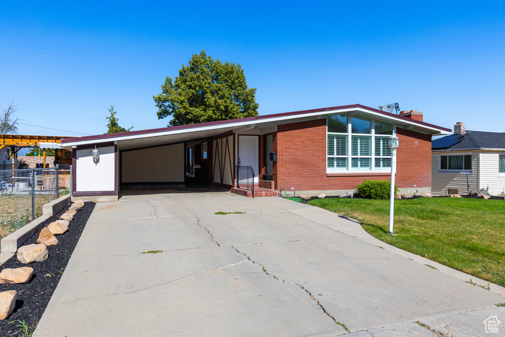 Mid-century modern home with brick siding, a carport, and concrete driveway