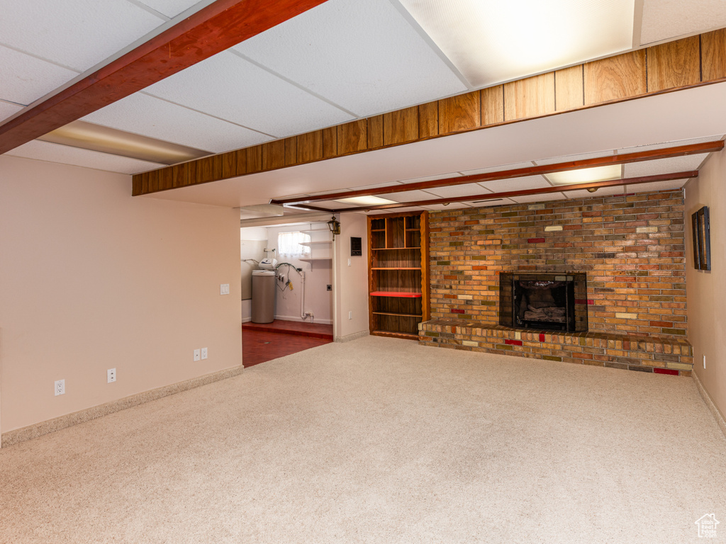 Unfurnished living room with carpet floors, a brick fireplace, and beam ceiling