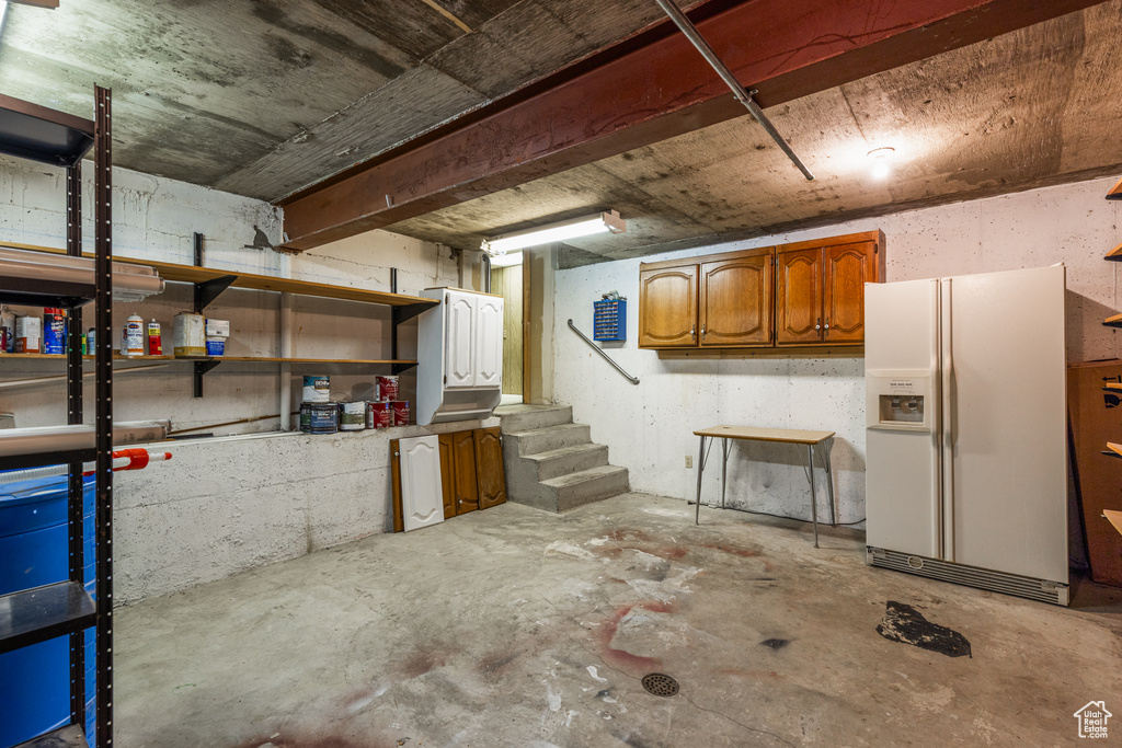Below grade area with white fridge with ice dispenser and stairway