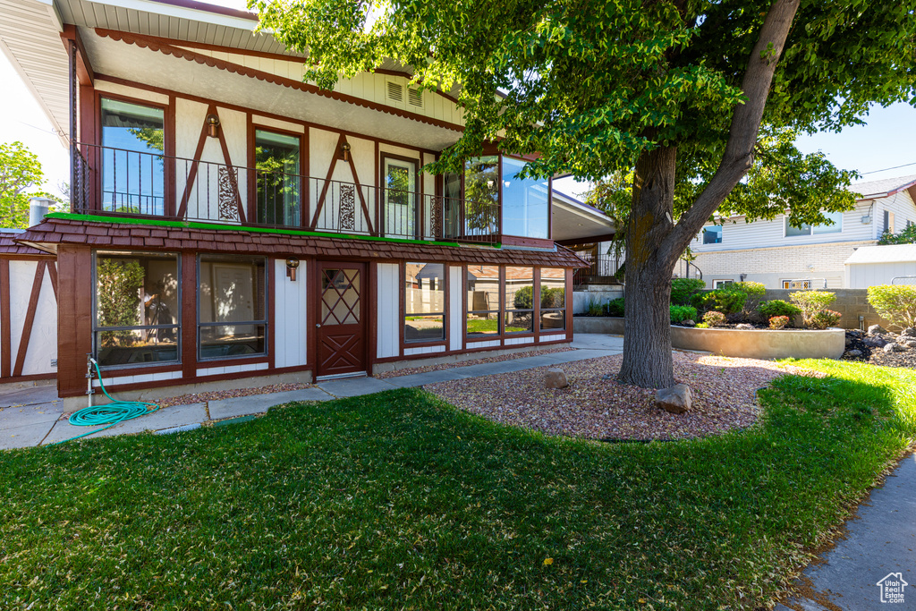 Entrance to property featuring a balcony, a yard, and stucco siding