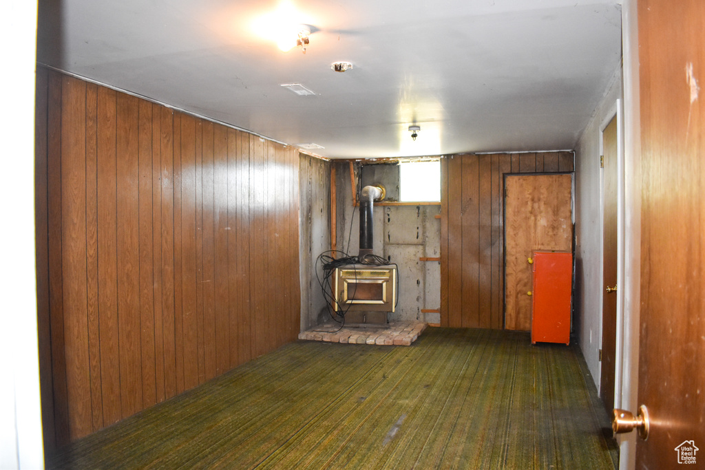 Unfurnished living room with a wood stove and wooden walls
