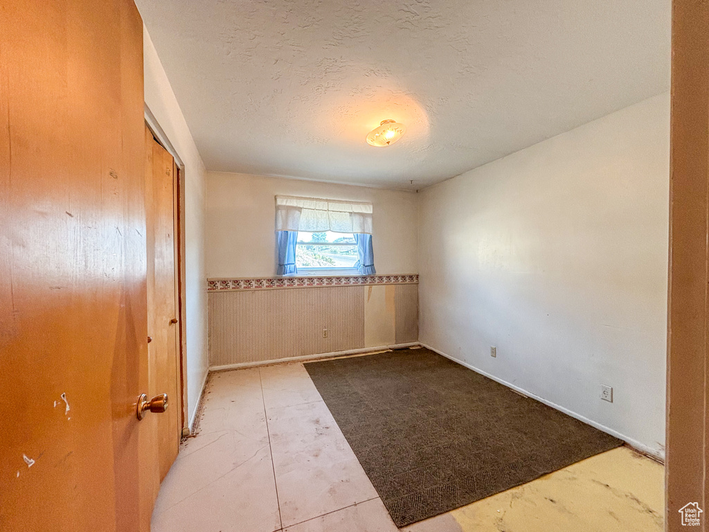 Unfurnished room with wainscoting and a textured ceiling