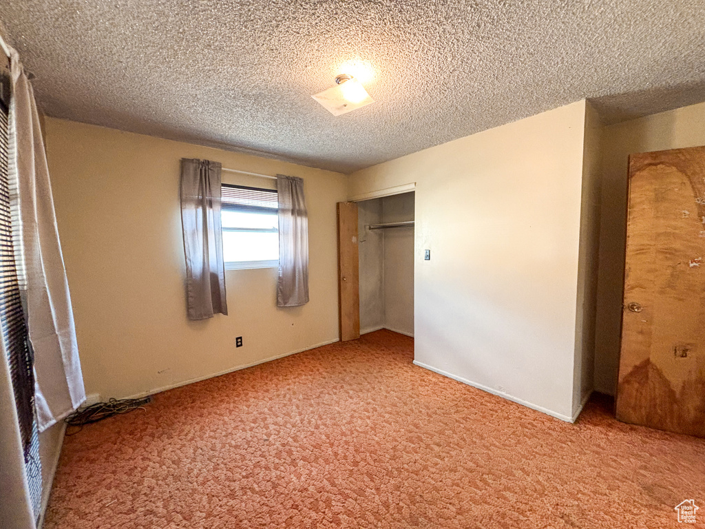 Unfurnished bedroom featuring carpet, a closet, and a textured ceiling