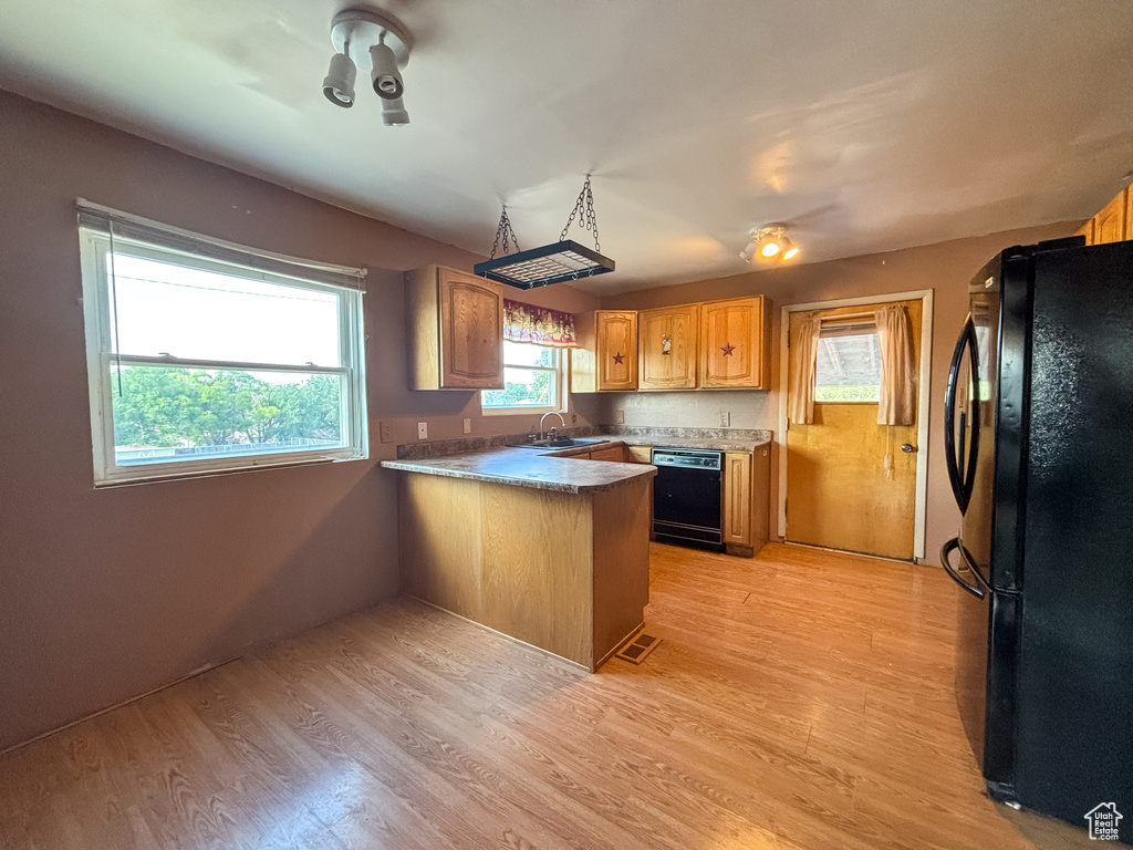 Kitchen featuring black appliances, a peninsula, and light wood-type flooring