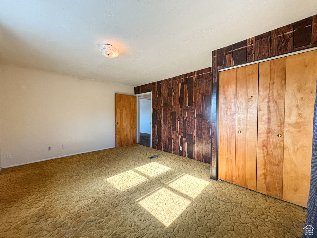 Unfurnished bedroom with wood walls and carpet flooring