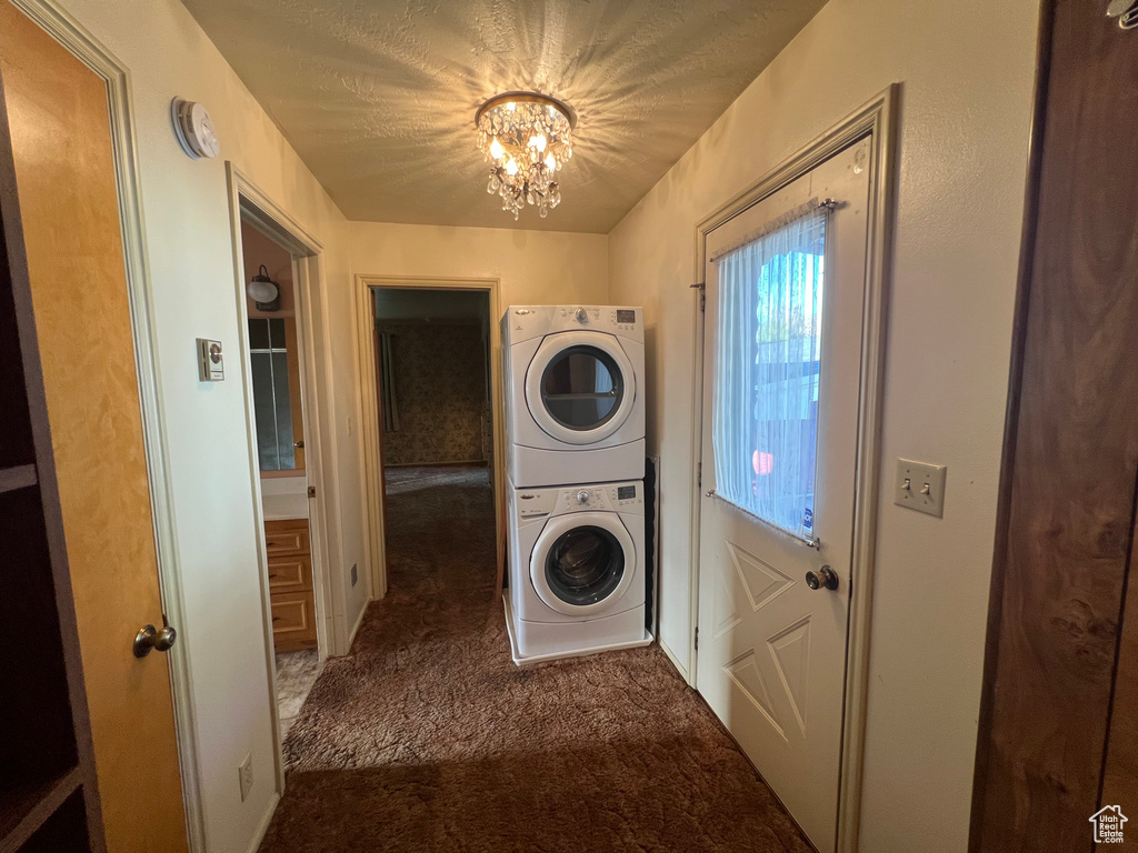 Laundry room with estacked washer and dryer, carpet floors, and a chandelier
