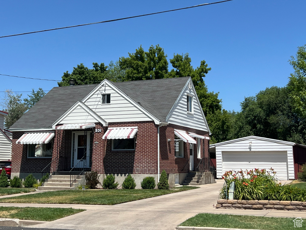 Bungalow-style home with an outbuilding, entry steps, brick siding, and a garage