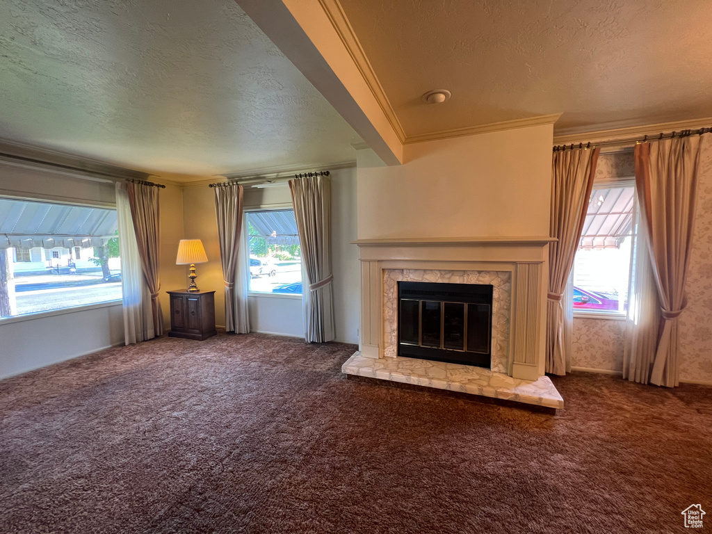 Unfurnished living room with a textured ceiling, carpet floors, a fireplace, and ornamental molding