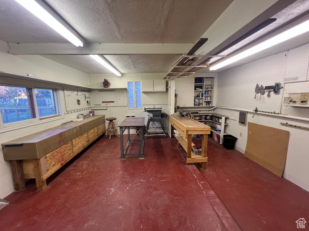 Miscellaneous room featuring a workshop area, concrete flooring, and a textured ceiling