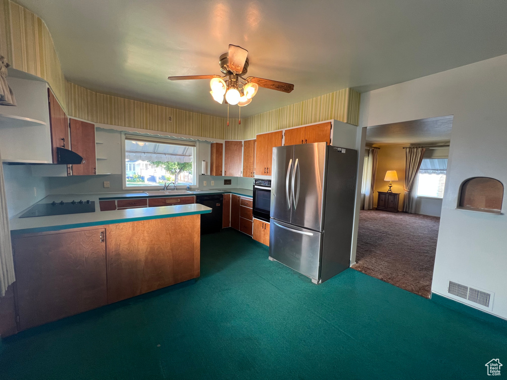 Kitchen featuring black appliances, dark colored carpet, a peninsula, ceiling fan, and healthy amount of natural light