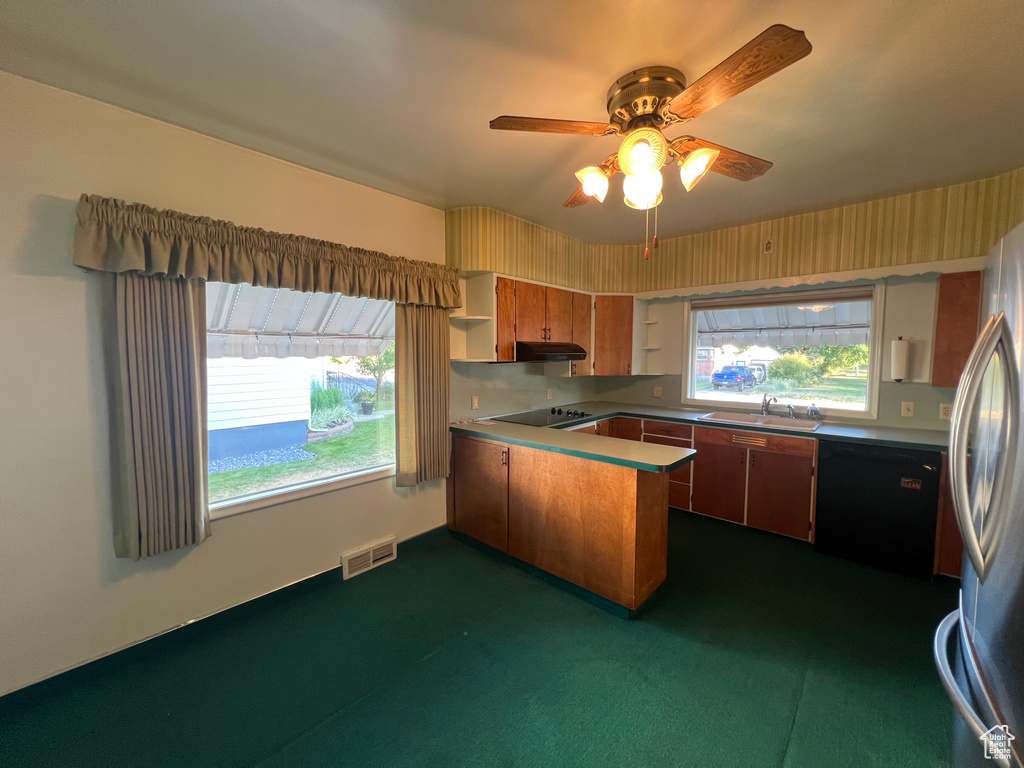 Kitchen with a peninsula, black appliances, under cabinet range hood, open shelves, and brown cabinetry