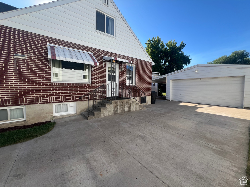 View of side of home with a garage and an outbuilding