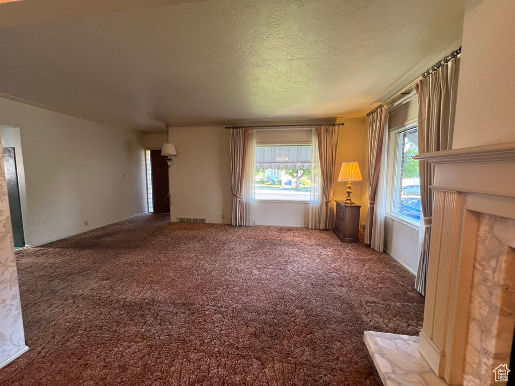 Unfurnished living room with carpet flooring and a textured ceiling
