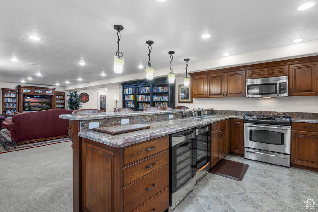 Kitchen with stainless steel appliances, wine cooler, open floor plan, a peninsula, and recessed lighting