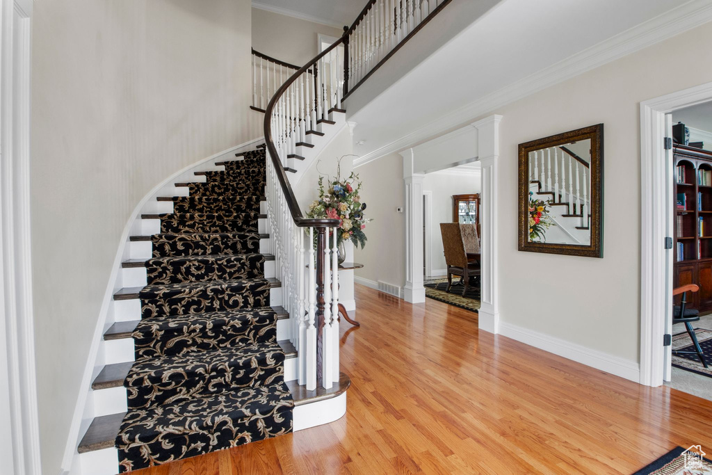 Staircase featuring wood finished floors, crown molding, and a towering ceiling
