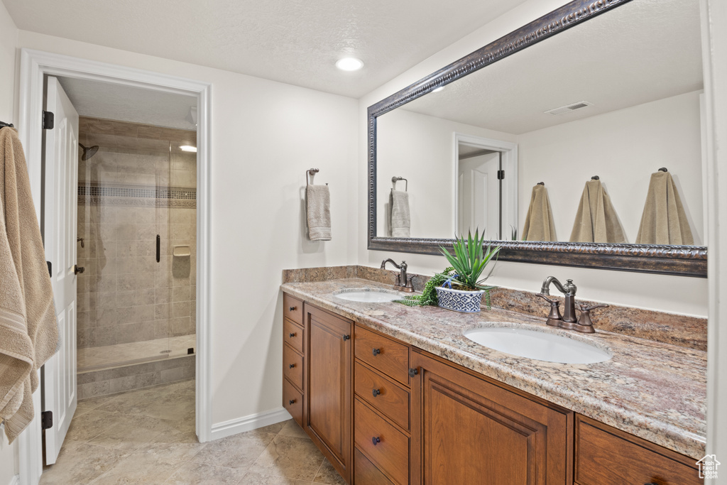Full bathroom featuring double vanity, a stall shower, tile patterned floors, and recessed lighting