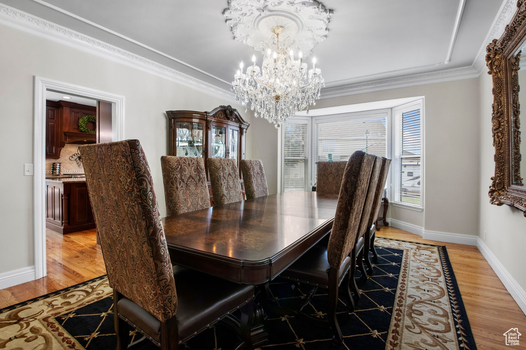 Dining area featuring a chandelier, light wood-style flooring, and ornamental molding