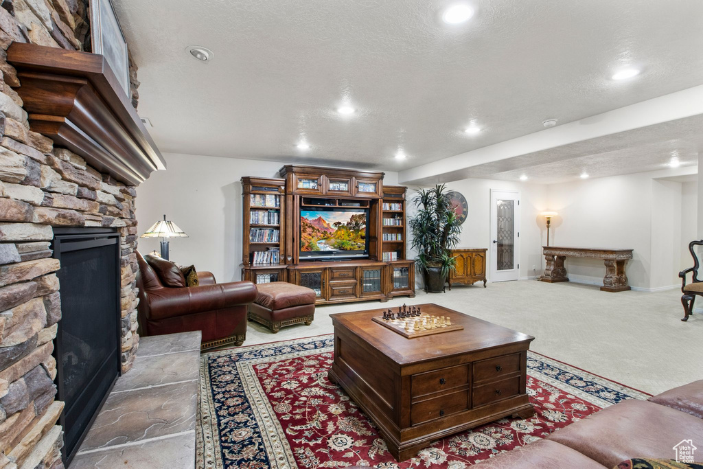 Living area with a stone fireplace, recessed lighting, and carpet