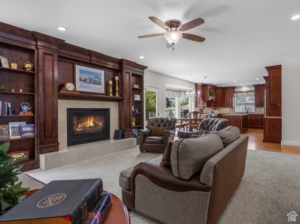 Living area with a fireplace, a ceiling fan, recessed lighting, light wood-type flooring, and light colored carpet