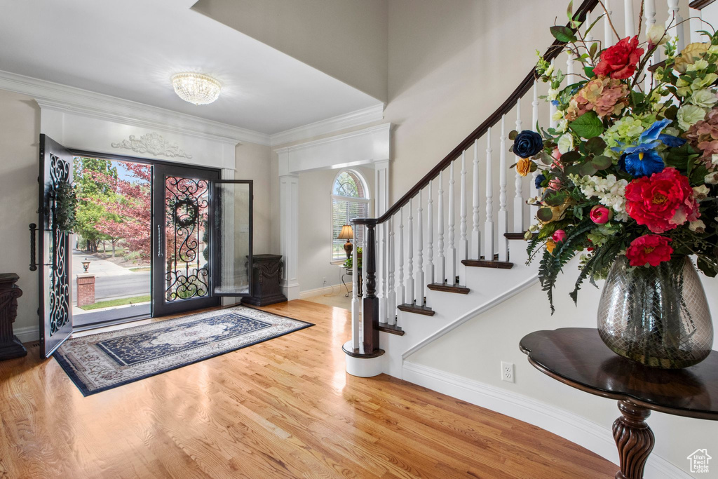 Entryway featuring wood finished floors, stairway, ornamental molding, and decorative columns