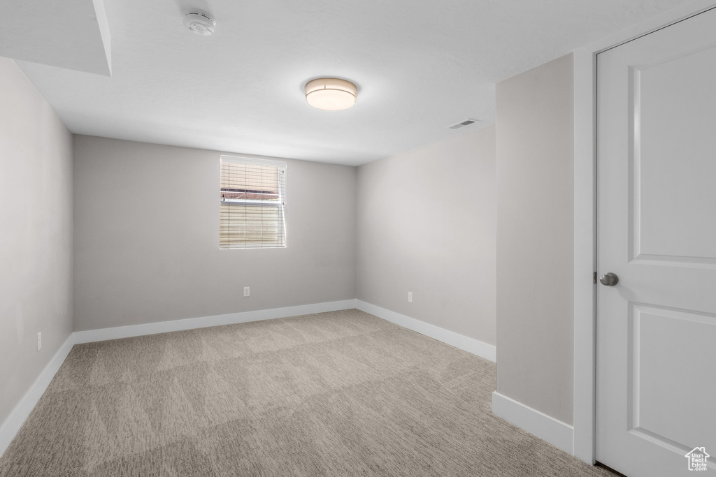 Carpeted spare room featuring a smoke detector and baseboards