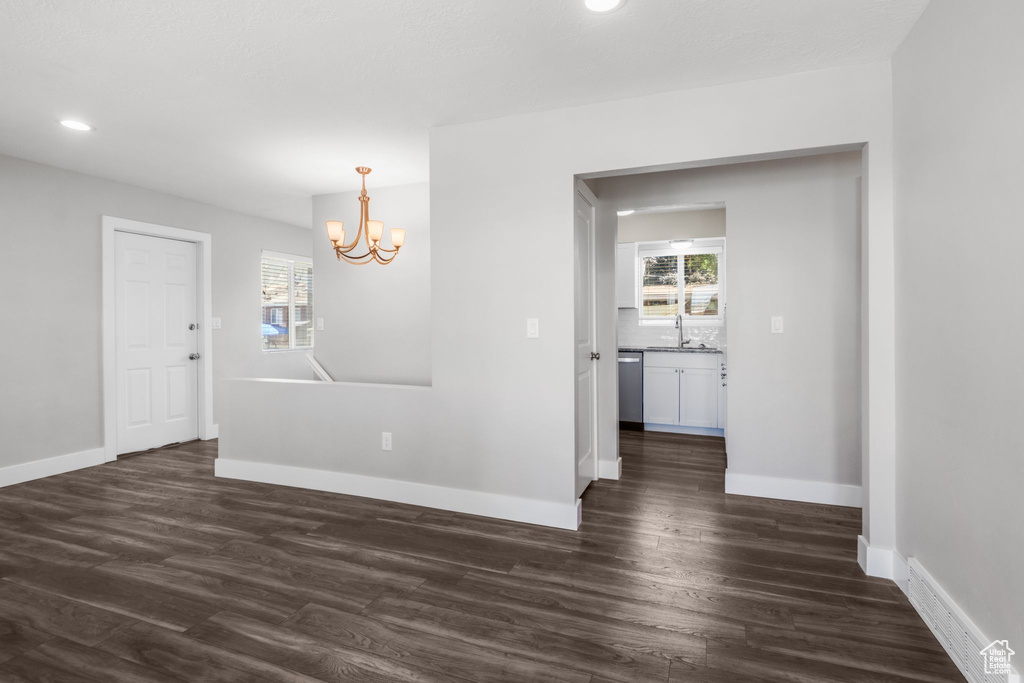 Unfurnished room featuring a chandelier, dark wood-style floors, healthy amount of natural light, and recessed lighting