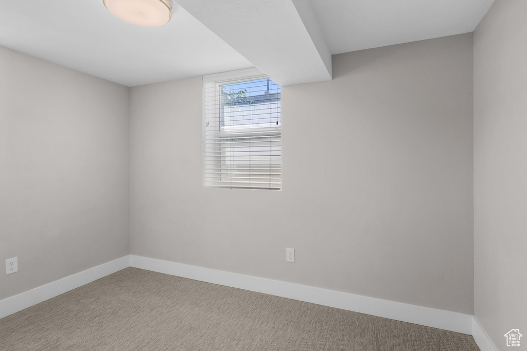 Carpeted spare room featuring baseboards