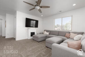 Carpeted living room with ceiling fan, recessed lighting, and a fireplace