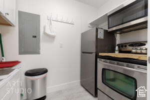 Kitchen with electric panel, stainless steel appliances, white cabinets, and light countertops