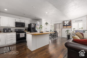 Kitchen with black appliances, a center island, white cabinetry, dark wood finished floors, and recessed lighting