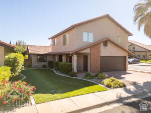 View of front of house with a front yard, concrete driveway, and stucco siding